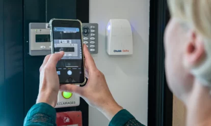 Personne qui tient un téléphone, qui scanne un QR Code d'un produit Chubb Delta