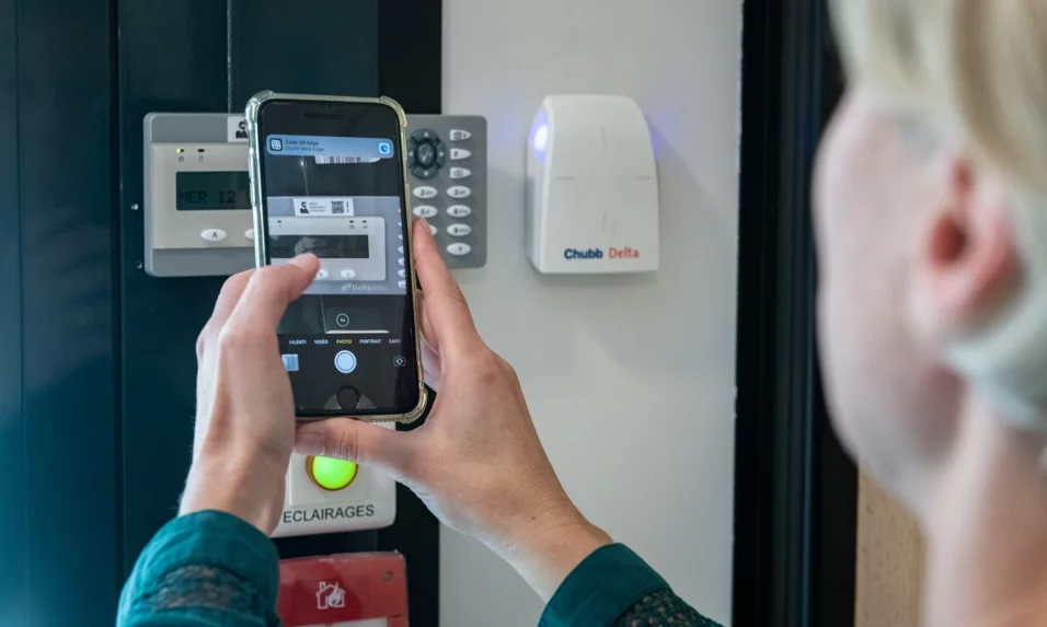 Personne qui tient un téléphone, qui scanne un QR Code d'un produit Chubb Delta