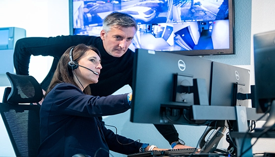 Femme avec un casque de télécommunication montrant son écran à un collègue