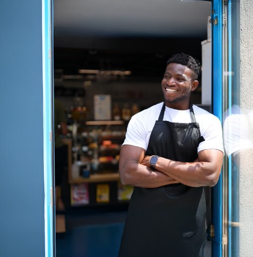 man outside shop with arms folded